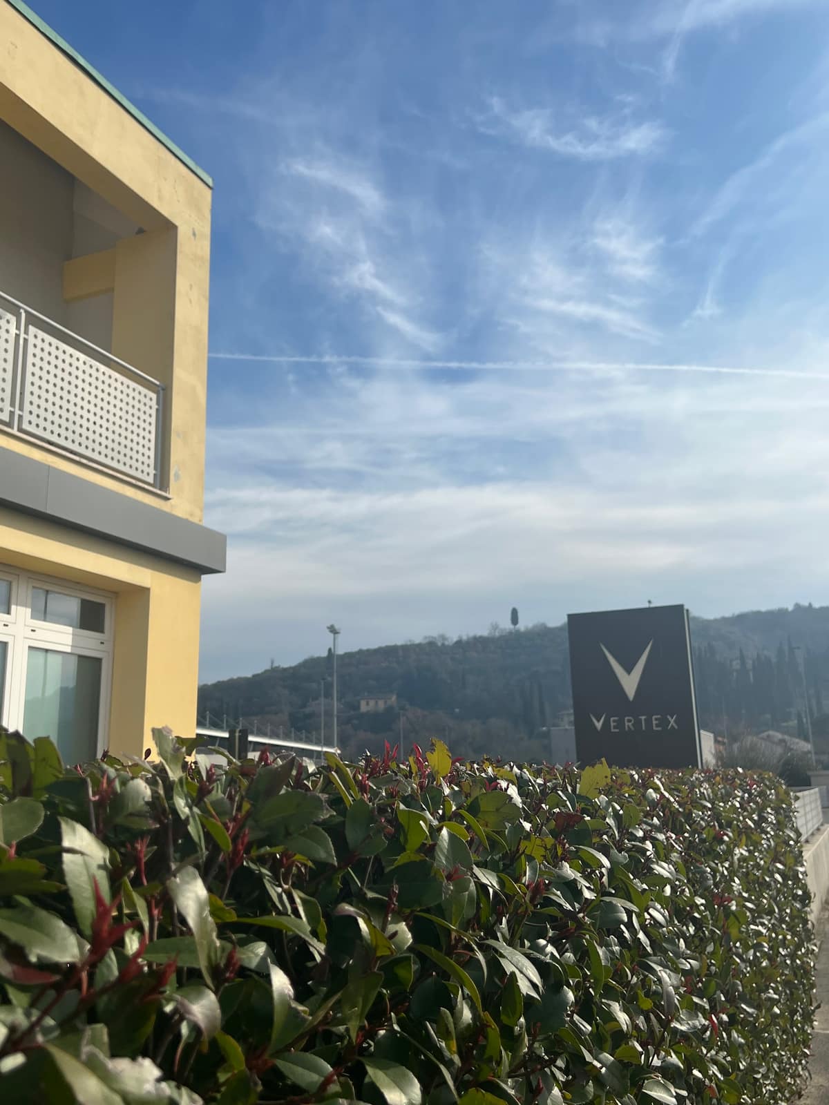 The Centro Vertex clinic in Arezzo, its dark monolith sign beside the building with the Tuscan hills behind
