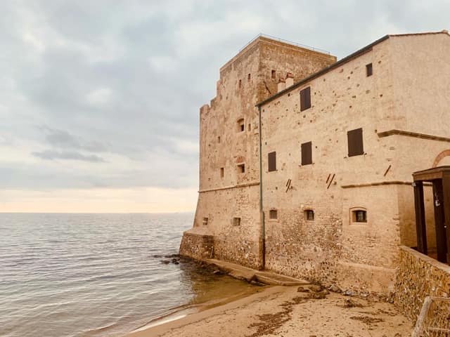 A medieval stone tower on the Tyrrhenian shore near Grosseto, the sea at its foot