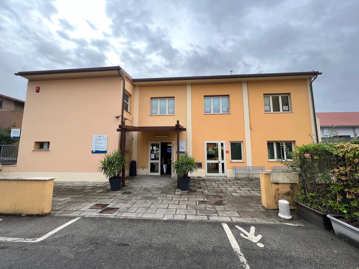 The entrance to Fondazione Turati Pistoia: a two-storey apricot building with a covered porch and potted palms